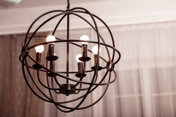 Fototapeta na wymiar Spherical art loft style chandelier with warm light bulbs