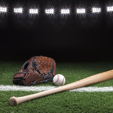 Baseball mitt ball and bat at night under stadium lights