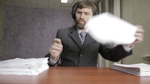 Businessman in headphones funy signing and stamping incoming documents.