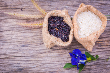 Black rice and Raw grain white rice in burlap bag on wood background,Jasmine rice,