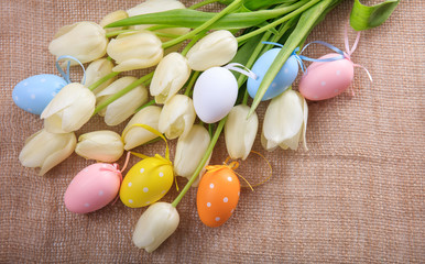 Fototapeta na wymiar Easter eggs and tulips on a burlap