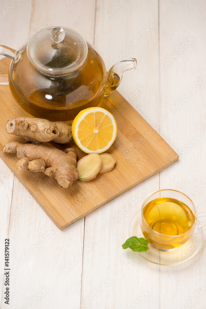 Wall mural Cup of ginger tea with lemon and honey on white wooden background.