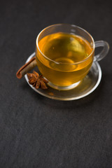 Cup of black tea with spices on white wooden background.