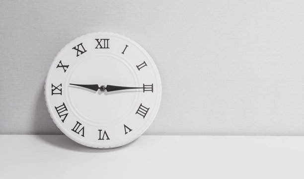 Closeup white clock for decorate show a quarter past nine or 9:15 a.m. on white wood desk and wallpaper textured background in black and white tone with copy space
