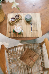 Cup of cappuccino on a wooden table. Bamboo style. Wicker bag on the chair