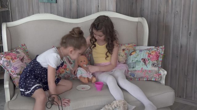 Little sister girls feed their doll