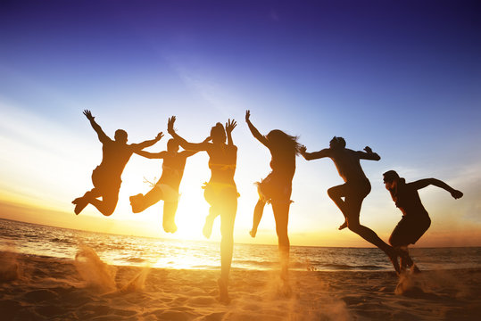 Happy friends jumps beach sunset. Friendship or team concept