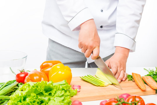 Chef cuts salad, prepares fresh vegetables on white background