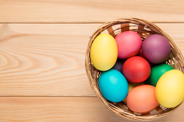 basket with Easter eggs on a wooden table top Photo