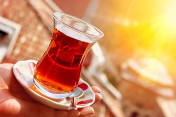 Tradition turkish tea in cup in woman hand with city roofs against