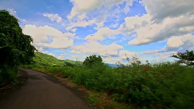 Motion along Curvy Country Road among Green Hilly Landscape