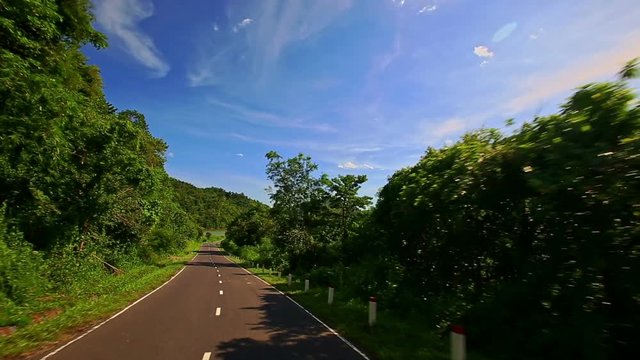 Camera Moves along Curvy Country Road among Hilly Landscape