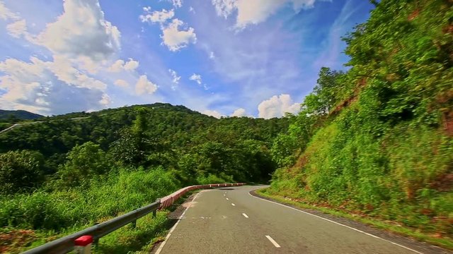 Camera Moves along Curvy Country Road among Hilly Landscape