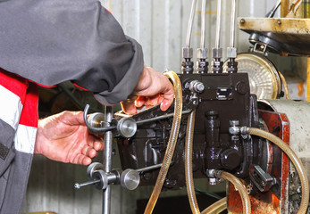 Professional mechanics testing diesel injector in his workshop, repair of diesel fuel injectors, ustroustvo for the diagnosis of fuel injectors