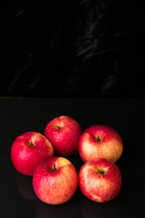 Red apples on black background. Wet. Copy space