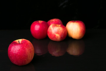Red apples on black background. Wet. Close up