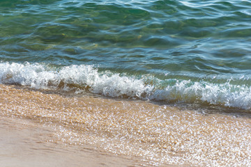 Fototapeta na wymiar Light waves washing up on a golden sand beach.