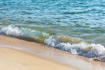 Light waves washing up on a golden sand beach.