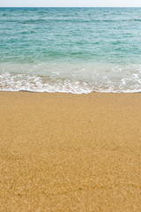 Fototapeta na wymiar Light waves washing up on a golden sand beach, with depth of field.