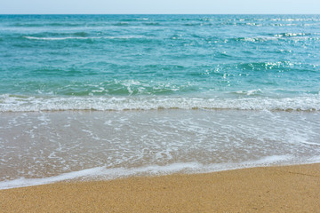 Fototapeta na wymiar Light waves washing up on a golden sand beach, with depth of field.