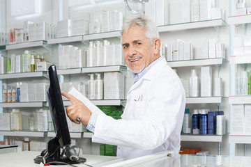 Smiling Pharmacist Touching Monitor Screen In Pharmacy