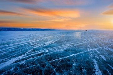 Beautiful view of cracked ice of a frozen lake Baikal during sunrise.