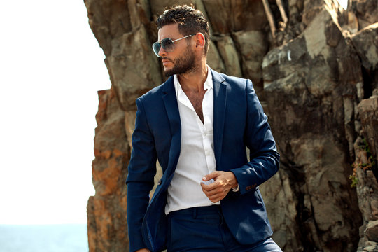 Man in elegant suite posing in rock background