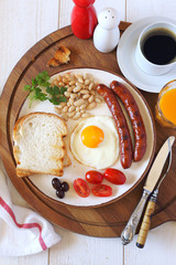 English breakfast with sausage, fried egg, baked beans and coffee. Top view