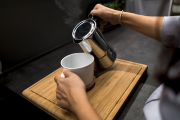 Fototapeta na wymiar woman holding coffee pot pouring coffee into white cup