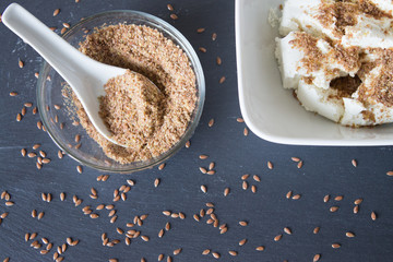Homemade cottage cheese cream with crushed flax seeds on stone background