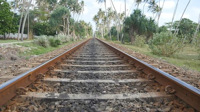 Camera move forward along the railway with exotic tropical nature at background. The rail tracks close up. Point of view of train moving along tracks in asia. Slow motion Close up