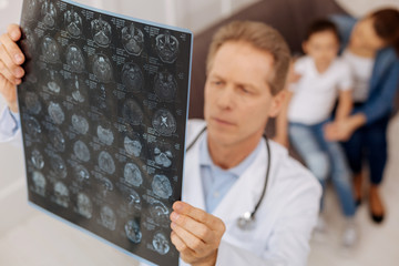 Worried focused neurosurgeon examining patients x-ray
