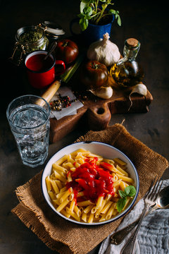 Plate of macaroni with tomato on dark grunge wooden background