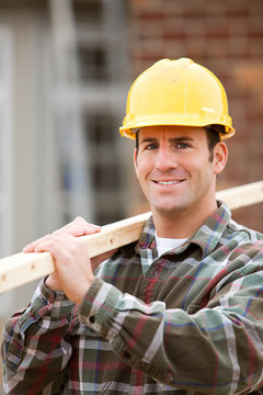 Construction: Worker Stands with 2x4 on Shoulder