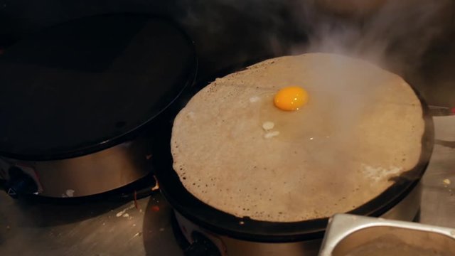 4K close up of a crepe heating with an egg on top. A crepe, or buckwheat pancake, in his cr&ecirc;perie restaurant, in Brittany. Galette bretonne, creperie, Rennes, Bretagne, France. French traditional food