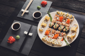Fototapeta na wymiar Set of sushi maki and rolls on black rustic wood