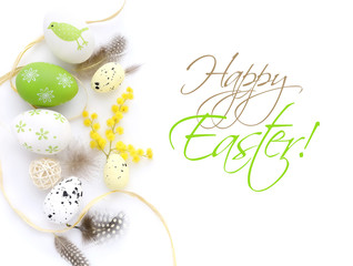 Easter eggs and mimosa flowers on white background with space for your text. Top view.