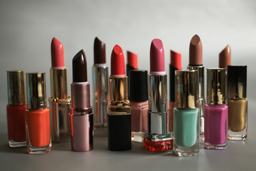 Lipsticks and nail polishes - cosmetics set on a gray background