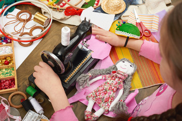 Fototapeta na wymiar girl sews doll clothes, top view, sewing accessories top view, seamstress workplace, many object for needlework, handmade and handicraft