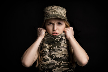 portrait of scared woman soldiers in military attire on black background