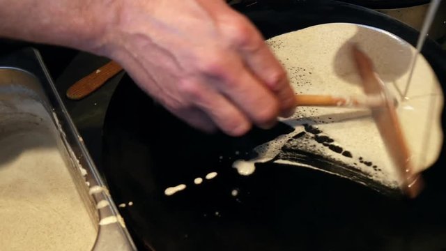 4K close up of a man spreading crepe batter a crepe, or buckwheat pancake, in his cr&ecirc;perie restaurant, in Brittany. French traditional food.  Galette bretonne, creperie, Rennes, Bretagne, France.