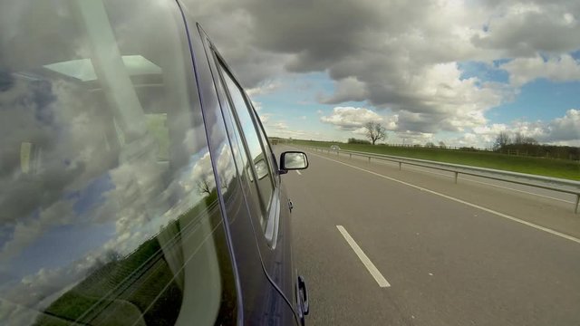 Car driving on a dual carriageway road with light traffic. Time lapse with reflections on the side of the vehicle. Vehicle POV.