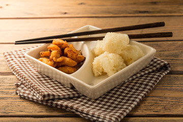 Sticky rice with fried chicken in food container on wood table.