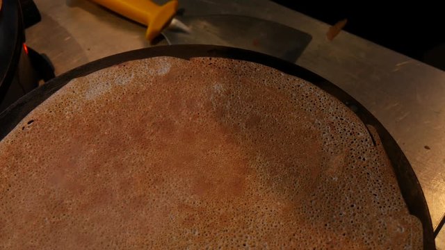 4K close up of a buckwheat crepe getting brown. A crepe, or buckwheat pancake, in his cr&ecirc;perie restaurant, in Brittany. Galette bretonne, creperie, Rennes, Bretagne, France. traditional food specialty