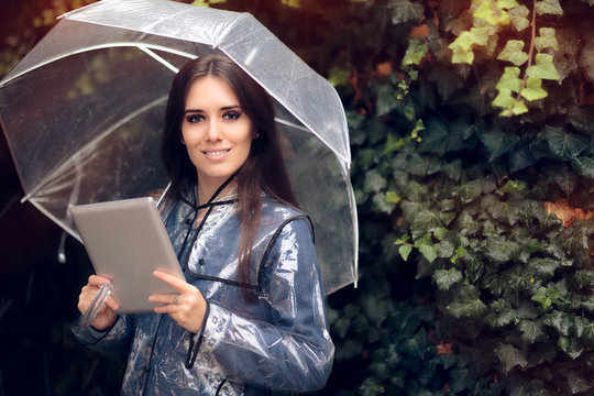 Smiling Woman with Raincoat and Umbrella Holding Pc Tablet