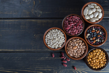 Obraz na płótnie Canvas Assortment of beans on wooden background. Soybean, red kidney bean, black bean,white bean, red bean and brown pinto beans