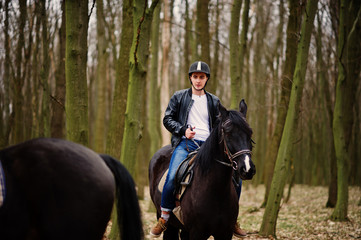 Fototapeta premium Young stylish man riding on horses at autumn forest.