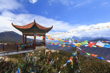 Fototapeta premium Meili snow mountain with Prayer flags and Chinese style roof, Deqing, Yunnan, China