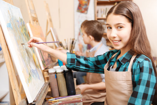 Charming young girl enjoying art lesson at school