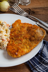 Fried pork chop in breadcrumbs, served with vegetable salad.